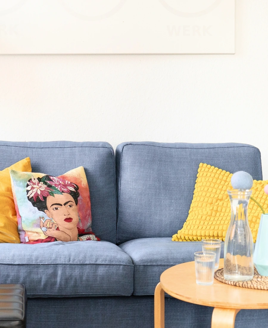 Das Sofo wo die Magie passiert. Auf dem Sofa sieht man einladende Pölster. Der Raum wirkt modern und gemütlich.