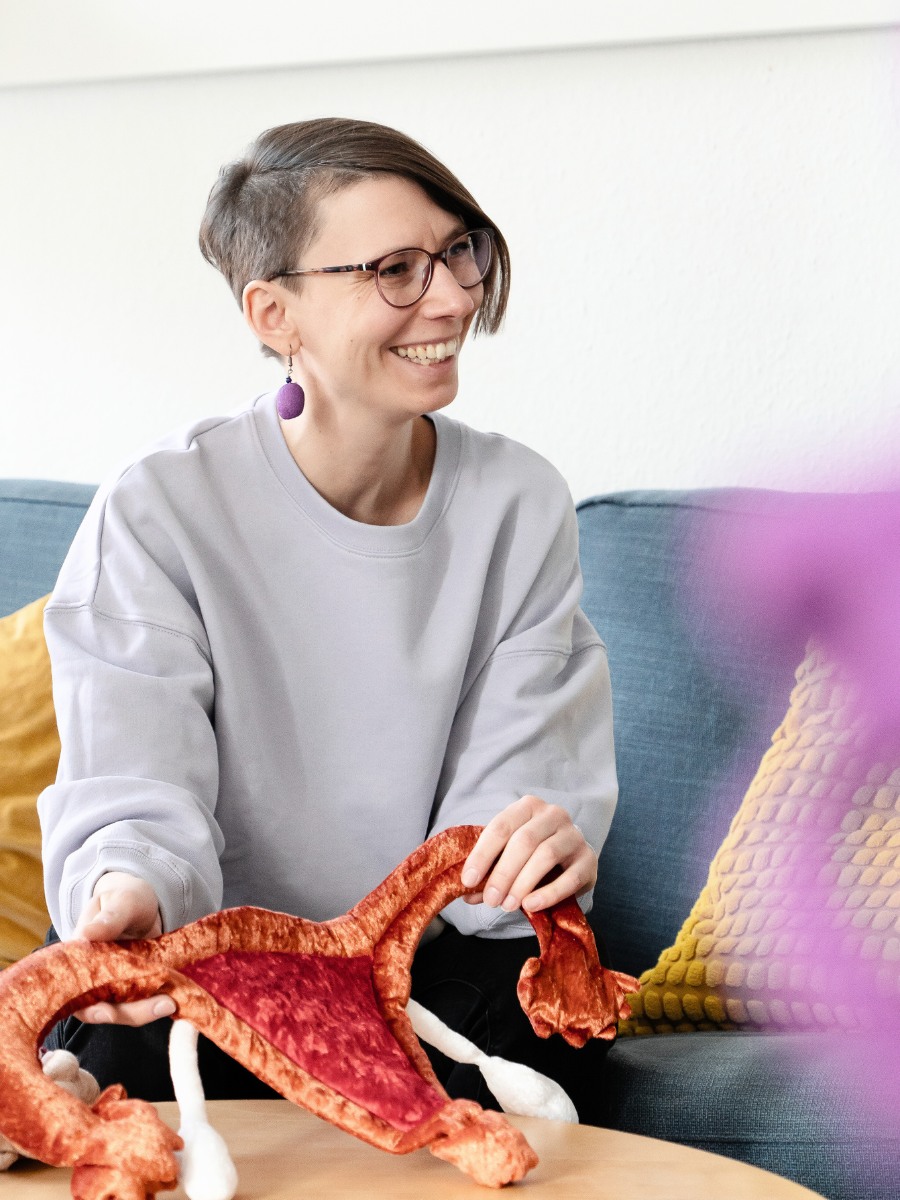 Ricarda Thiele bei der Einzelberatung über Zykluswissen Graz. Sie hält einen Stoff-Uterus in der Hand und lächelt freundlich.