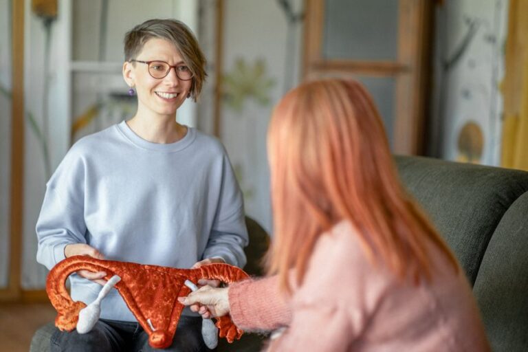 Ricarda Thiele berät eine Frau und hält dabei eine Stoff-Gebärmutter in Händen
